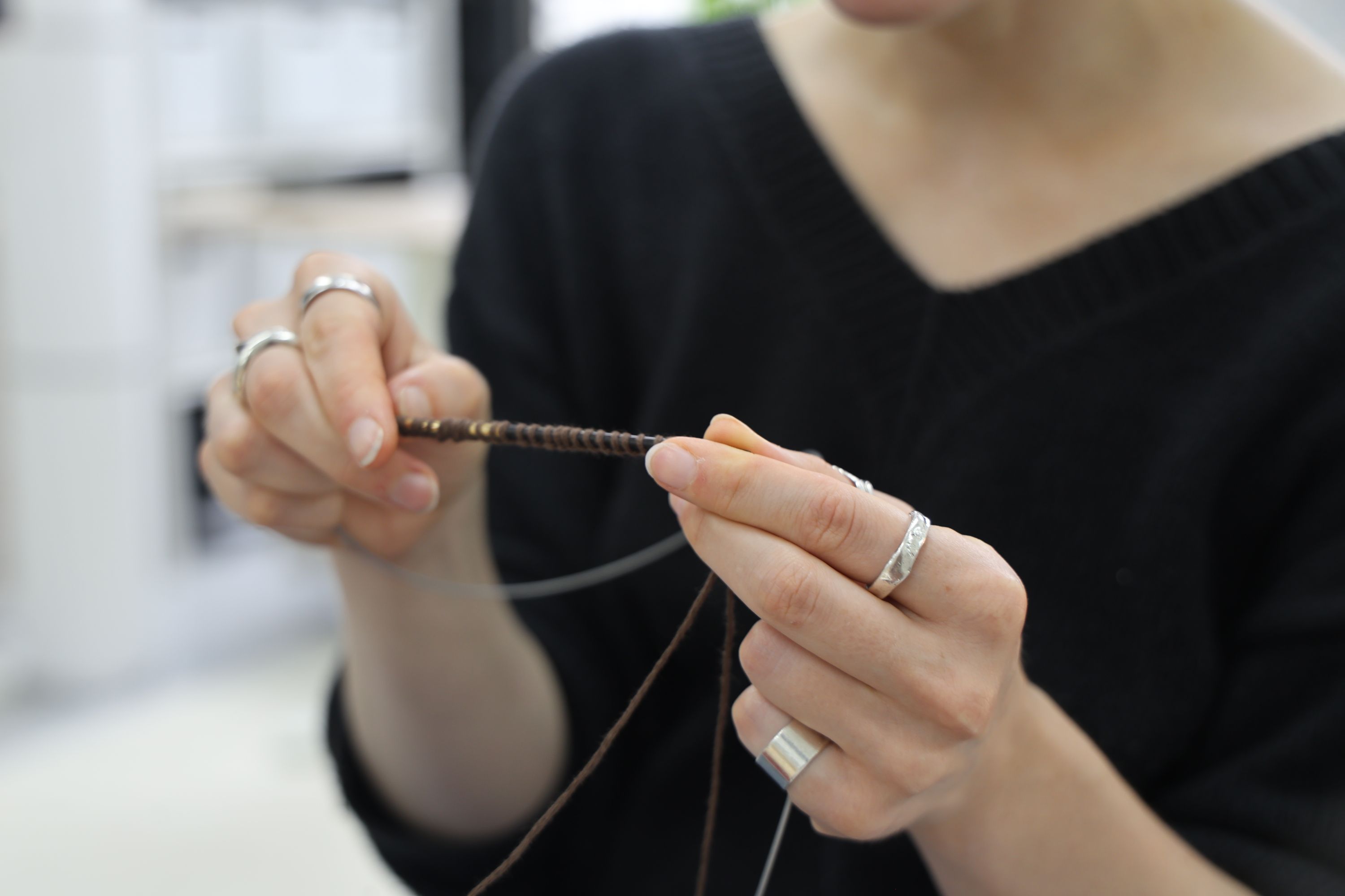 Close-up of hands demonstrating knitting technique with circular needles