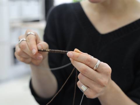 Close-up of hands demonstrating knitting technique with circular needles