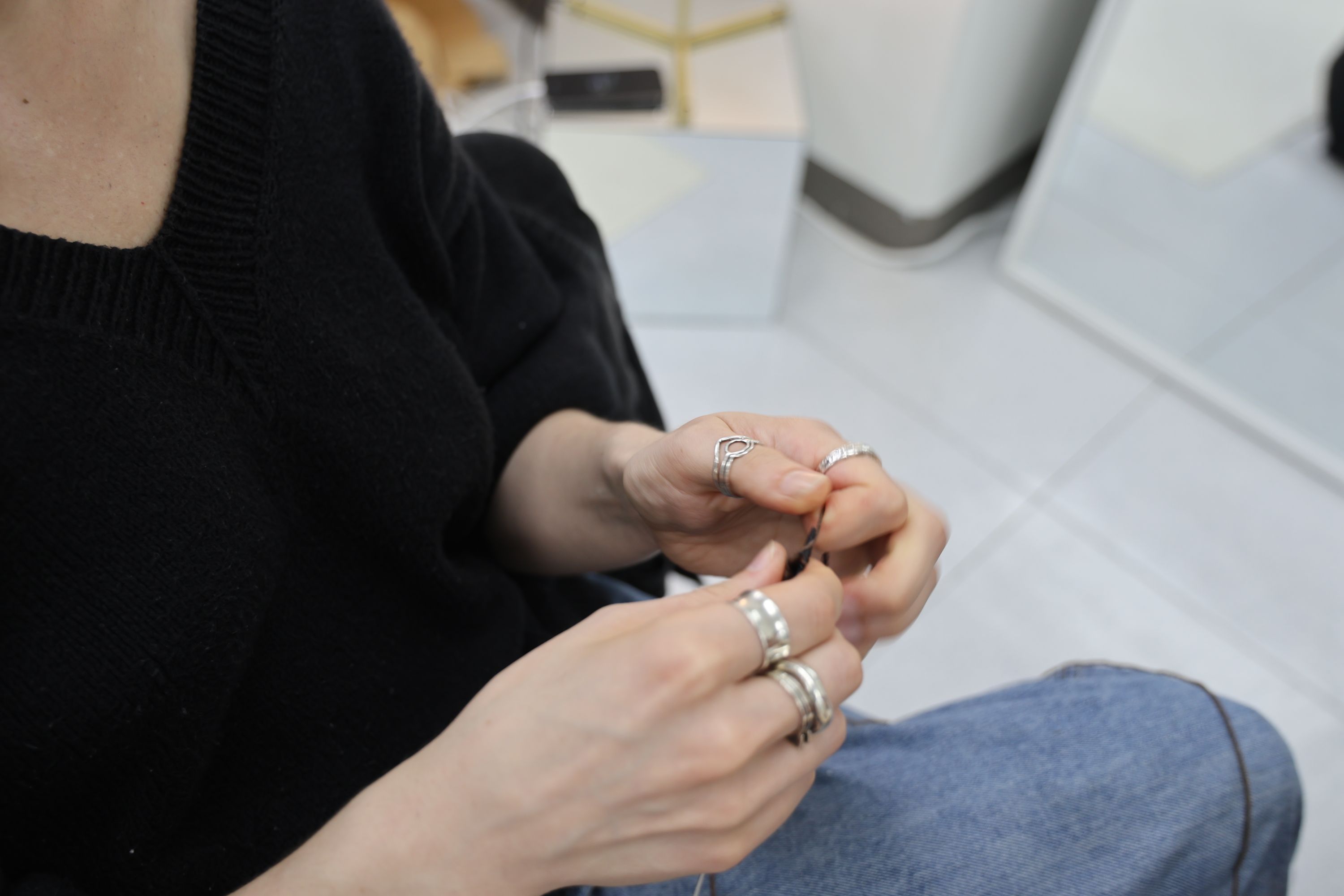 Participant's hands working with dark yarn during the knitting workshop