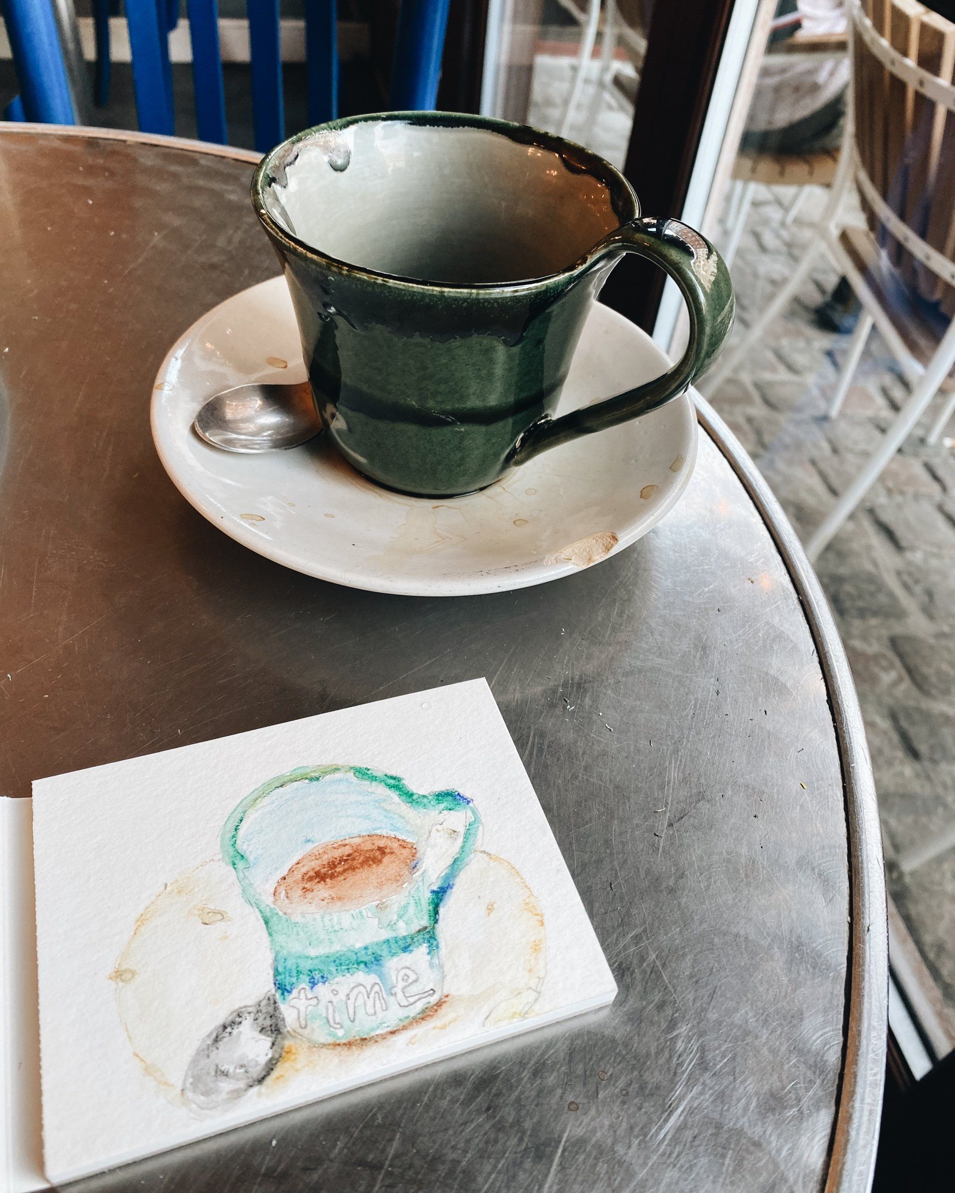 Watercolor drawing of a green coffee cup next to the real cup