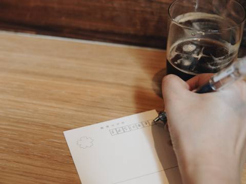 Writing an address on a postcard over coffee