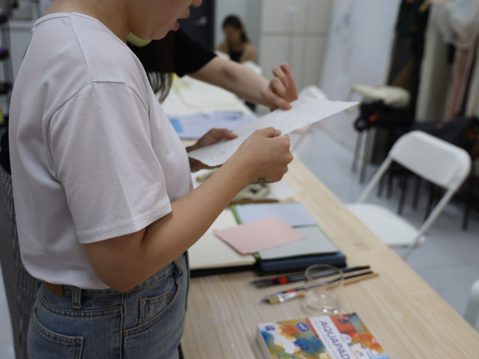 A participant reading a printed handout at the table — Material Lab × AI Archiving, July 15, 2026