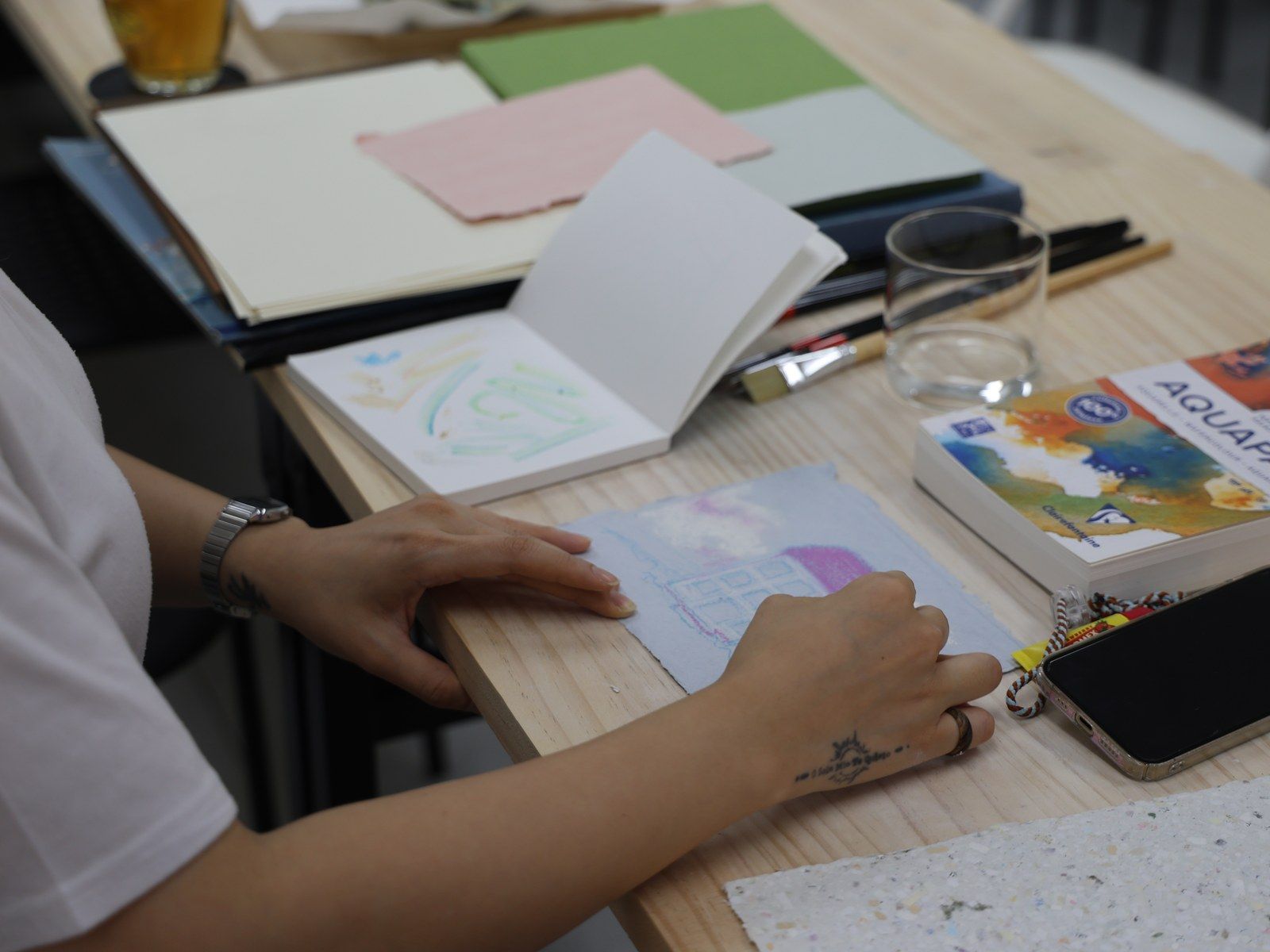 A sketchbook and colored paper swatches on the table — Material Lab × AI Archiving, July 15, 2026