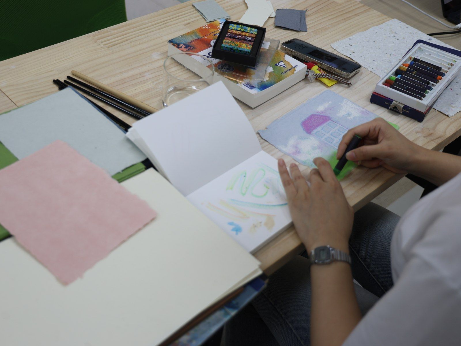 A participant drawing with a green pastel in a sketchbook — Material Lab × AI Archiving, July 15, 2026
