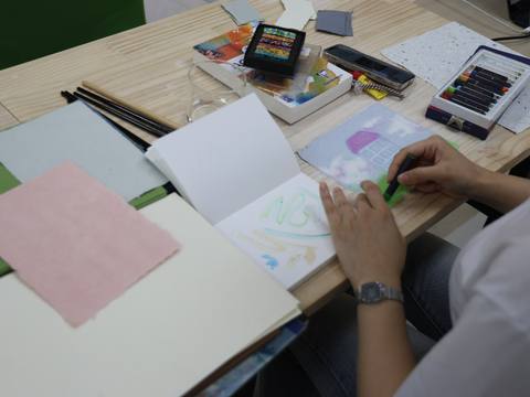 A participant drawing with a green pastel in a sketchbook — Material Lab × AI Archiving, July 15, 2026