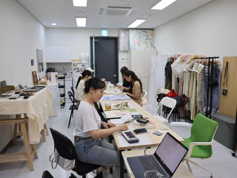 Participants working at long tables with a laptop open — Material Lab × AI Archiving, July 15, 2026