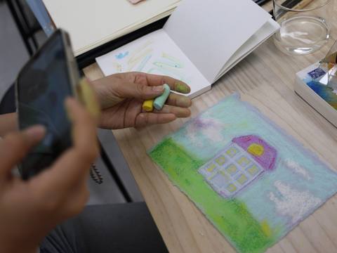 A hand holding a pastel above a finished house illustration — Material Lab × AI Archiving, July 15, 2026