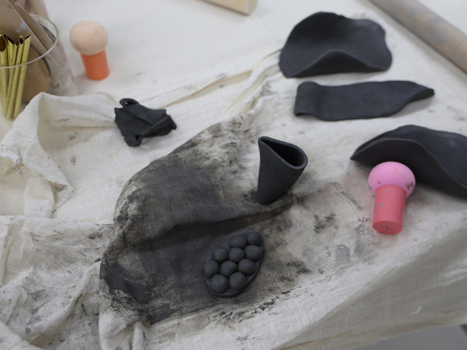 A hand pointing at a small stamped clay tile beside a pastel drawing — Material Lab × AI Archiving, July 15, 2026